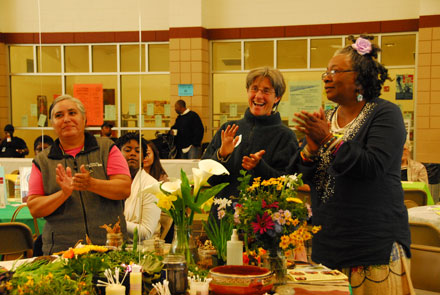 Women standing around table of flowers